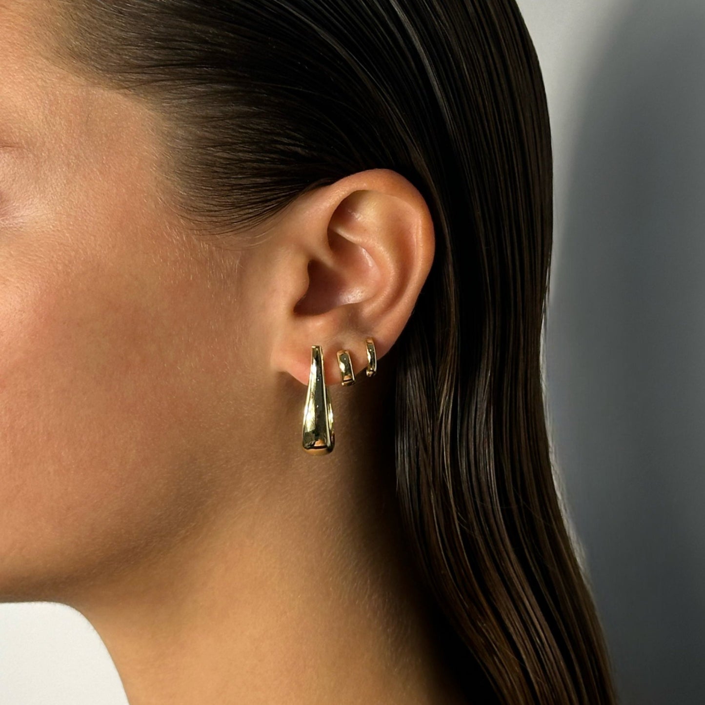 woman wearing 14k gold straight curve unique classic timeless statement long hoop earrings