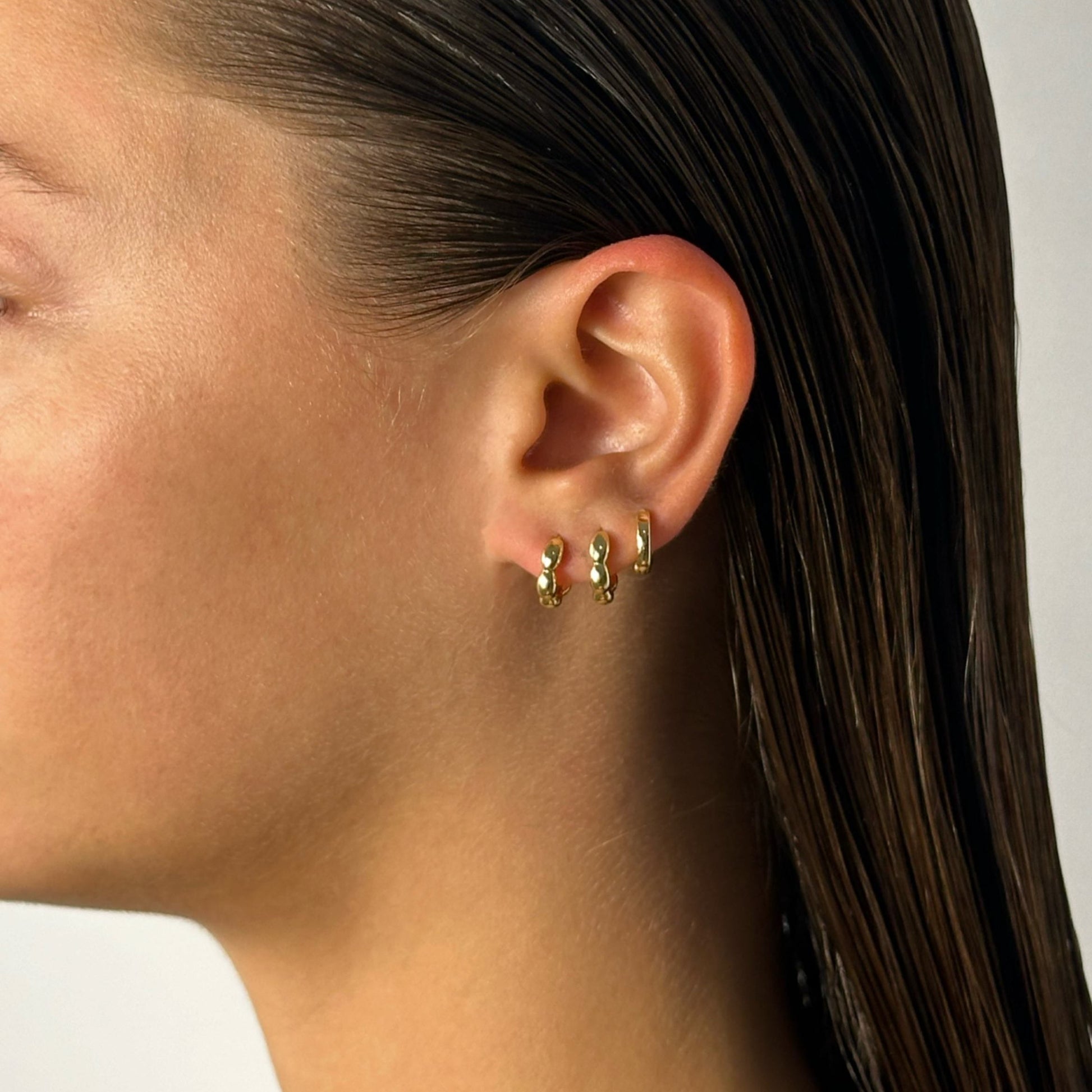 lady wearing gold bubble huggie hoops 