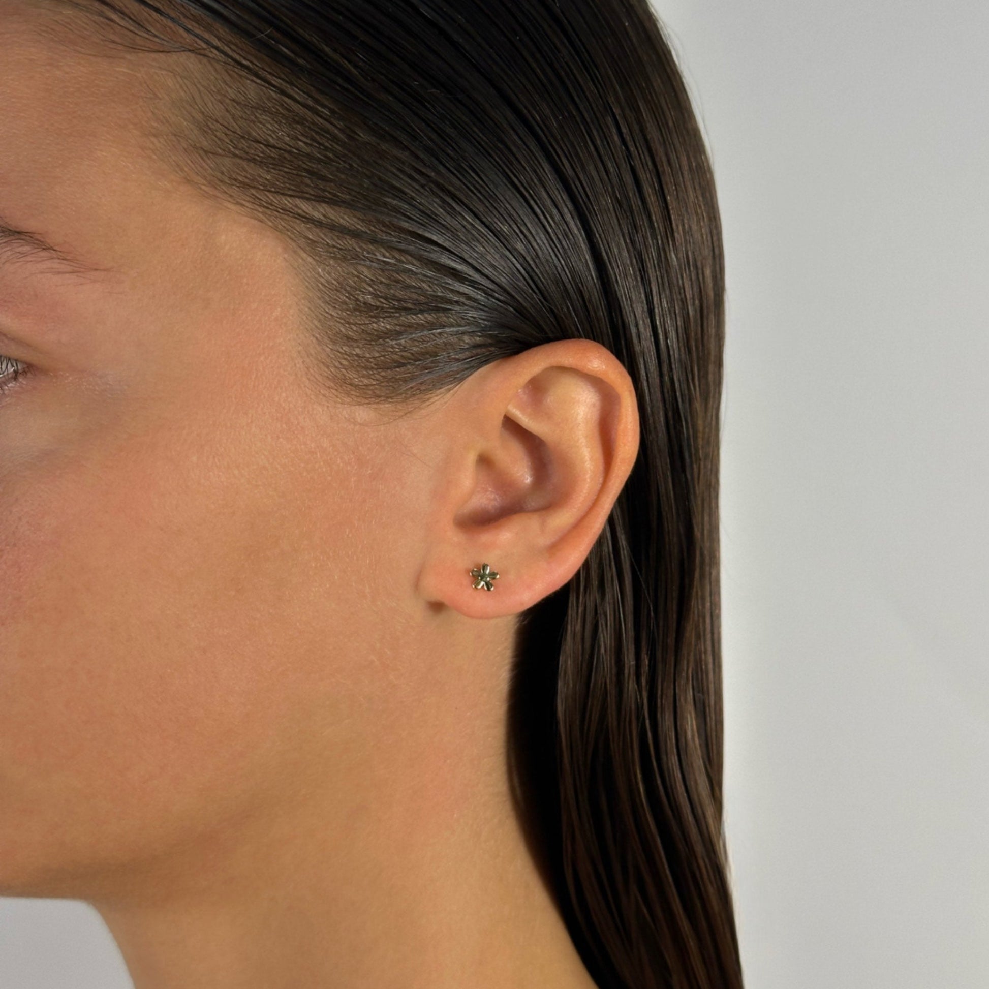 woman wearing gold classic flower stud earrings 