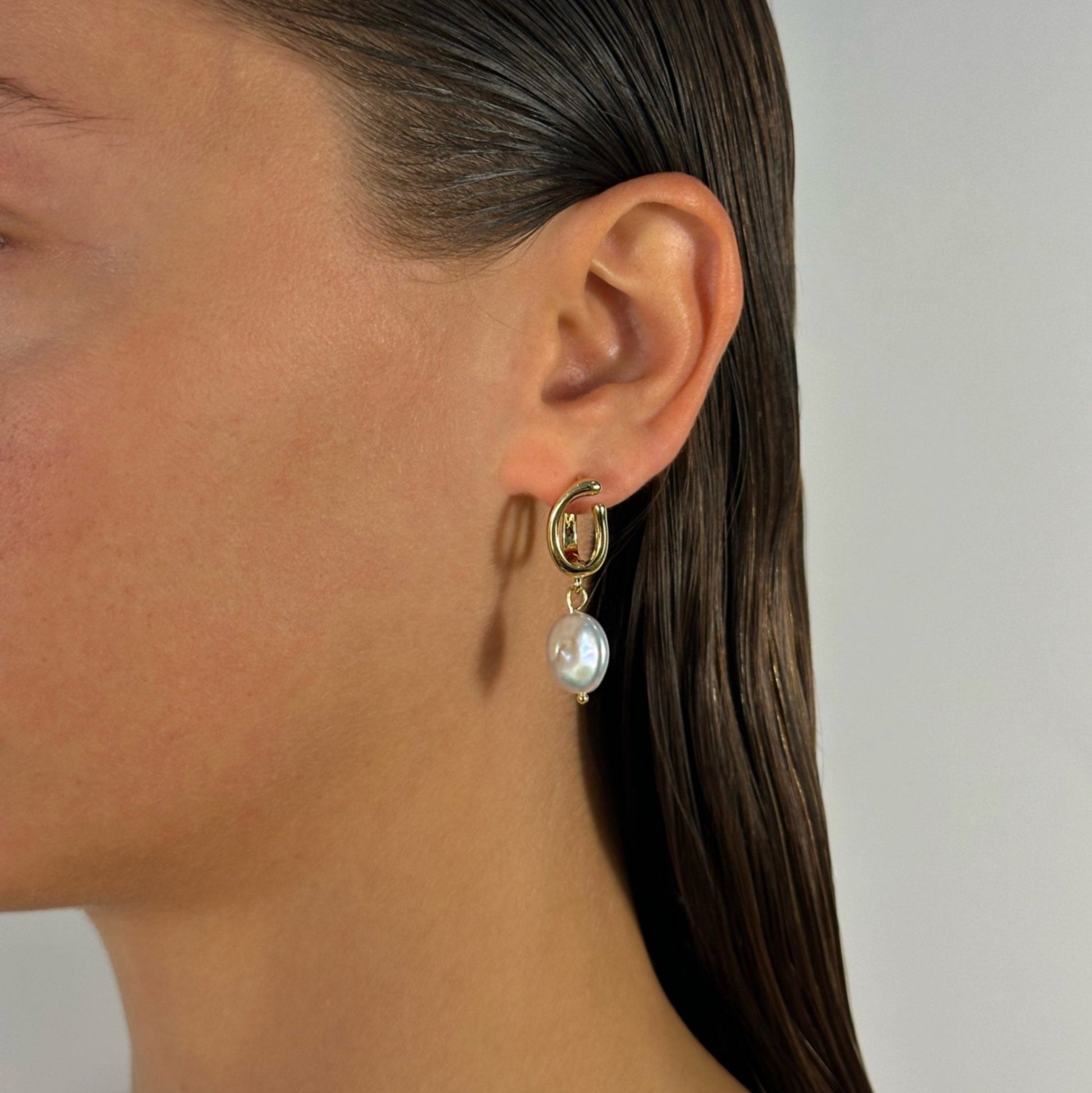 woman wearing gold freshwater pearl drop earrings